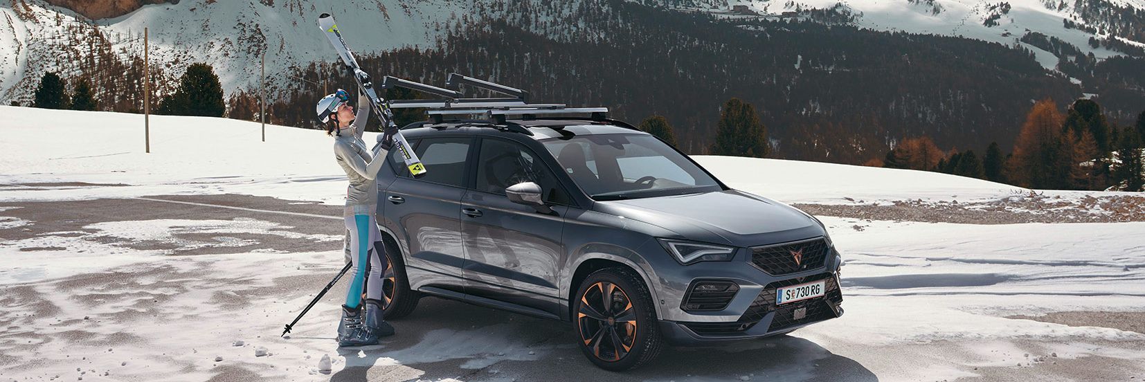 Eine Frau befestigt ihre Ski am Skiträger eines CUPRA Ateca