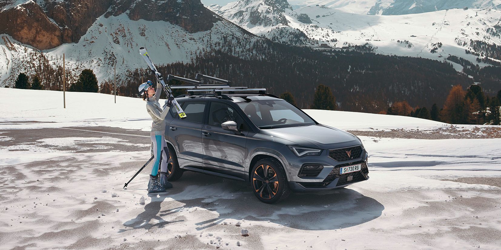 Eine Frau befestigt ihre Ski am Skiträger eines CUPRA Ateca