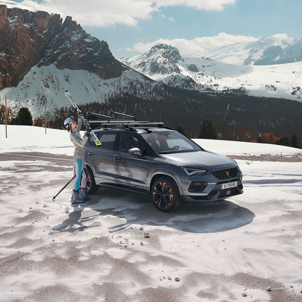 Eine Frau befestigt ihre Ski am Skiträger eines CUPRA Ateca