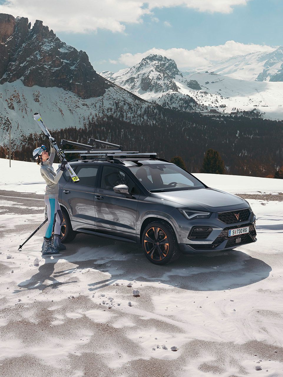 Eine Frau befestigt ihre Ski am Skiträger eines CUPRA Ateca