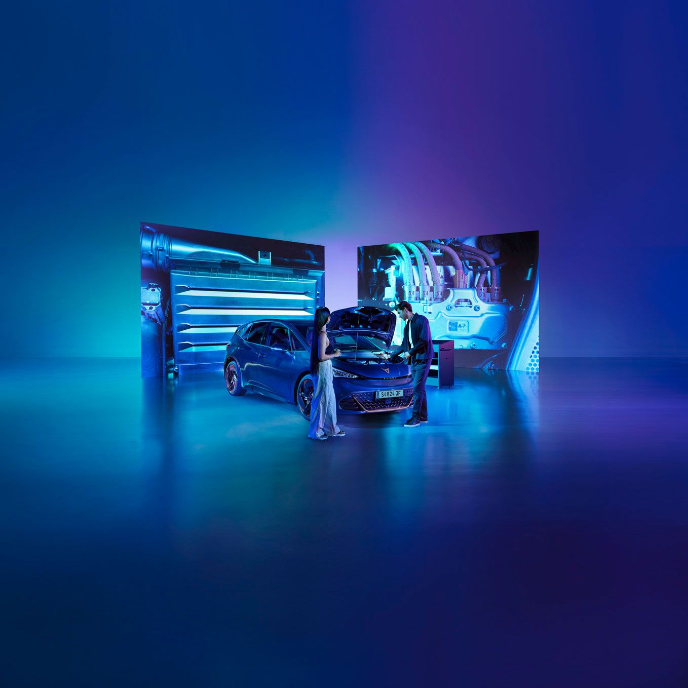 Eine Frau und ein Mann blicken bei geöffneter Kühlerhaube auf den Motor eines CUPRA Born